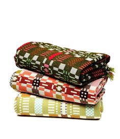 three blankets stacked on top of each other in different colors and patterns, with one blanket folded