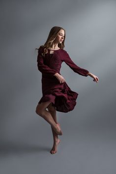 a woman in a red dress is dancing with her legs spread out and arms outstretched