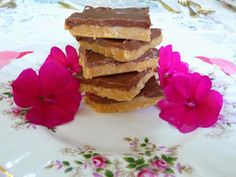 chocolate and peanut butter squares stacked on top of each other with pink flowers in the background