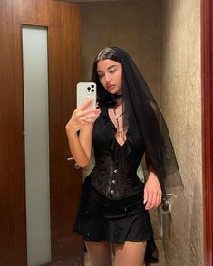 a woman taking a selfie in a bathroom mirror wearing a black corset