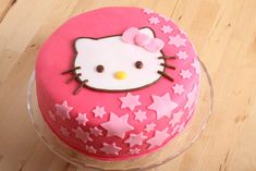 a pink hello kitty cake with stars on it sitting on top of a wooden table