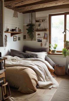 a bed sitting under a window next to a wooden shelf filled with books and plants