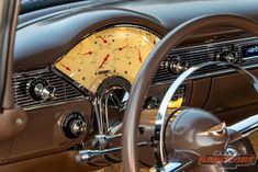 the interior of an old car with gauges and steering wheel