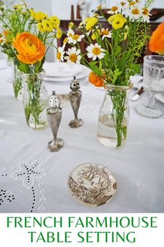 there is a table setting with flowers in vases and plates on the table top