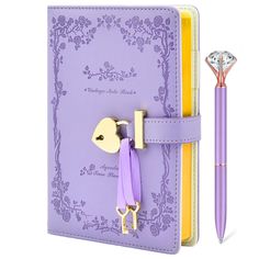 a purple notebook with a key attached to it and a pen next to it on a white background