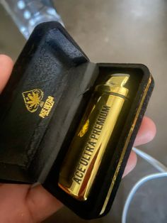 a person is holding an open box with a gold lighter in it's left hand