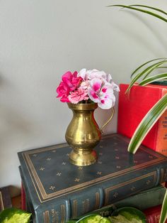 a gold vase filled with pink and white flowers on top of two green bookends