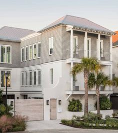 a large white house with lots of windows and palm trees in front of the building