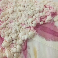 a white and pink piece of fabric with small rocks on it