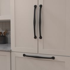 a kitchen with white cabinets and black handles