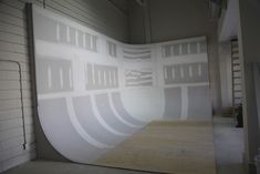 a skateboard ramp in the middle of a room with white walls and windows on it