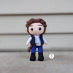 a small crocheted doll is posed in front of a building with a button on it