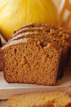 sliced loaf of pumpkin bread sitting on top of a cutting board next to an orange pumpkin