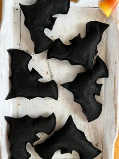 four black bats sitting on top of a white tray next to orange and yellow bottles