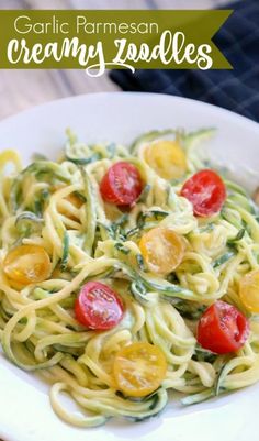 a white plate topped with pasta covered in pesto and cherry tomatoes next to a fork