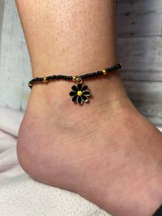 Black Beaded Anklet with Gold Accents and Black Flower Charm Length: 10" - 11 1/2" Handmade Black Flower Bracelets, Black Bohemian Anklets For Party, Bohemian Black Anklets For Party, Black Flower Shaped Beaded Bracelets For Gift, Black Flower Shaped Beaded Bracelets, Black Flower Beaded Bracelets For Gift, Handmade Black Anklets For Summer, Handmade Black Summer Anklets, Black Beaded Bracelets For Summer With Round Beads