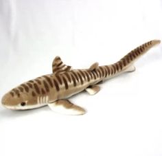 a stuffed shark is laying down on the white surface with it's mouth open