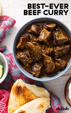 beef curry in a bowl with pita bread and cucumber on the side