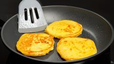 three pancakes are being cooked in a frying pan with a spatula on the side