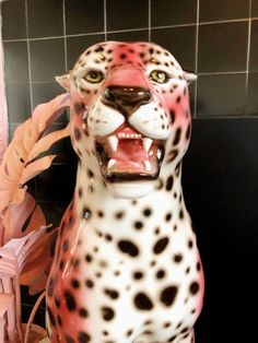 a statue of a cheetah with its mouth open in front of a tiled wall