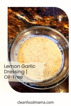 a glass bowl filled with liquid sitting on top of a marble counter next to a bottle of lemon garlic dressing