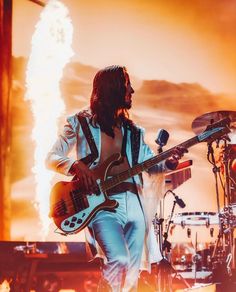 a man with long hair playing guitar on stage