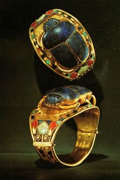 two gold rings with blue and red stones on the sides, one is shaped like a turtle