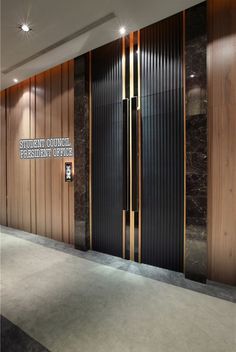 an empty room with wooden doors and black marble wall covering the entire area in front of it