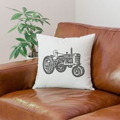 a brown leather chair with a white pillow on it and a potted plant in the background