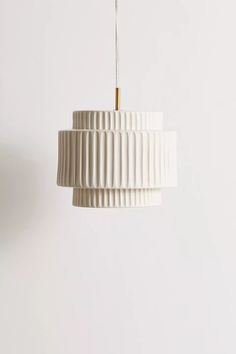 a white lamp hanging from a ceiling in front of a white wall with a light fixture on it