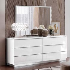 a white dresser sitting next to a wall with a large mirror on top of it