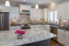 a large kitchen with white cabinets and granite counter tops, along with stainless steel appliances