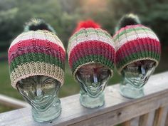 three knitted hats sitting on top of glass head mannequin's heads