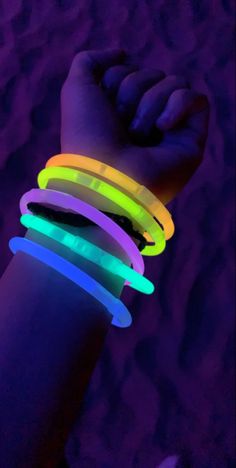 a person's arm with glowing bracelets on it