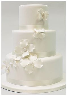 a three tiered white wedding cake with flowers on it