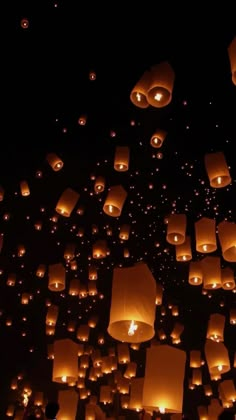 many lanterns are floating in the air at night