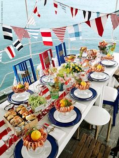 a long table set with plates and bowls filled with food on the deck of a boat