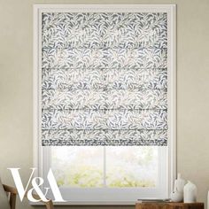 a window with blue and white roman blinds in front of the window, next to a dresser