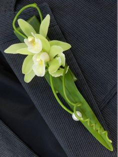 a boutonniere with white flowers and green leaves on it's lapel