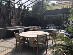 an outdoor dining area with chairs, tables and potted plants in the foreground