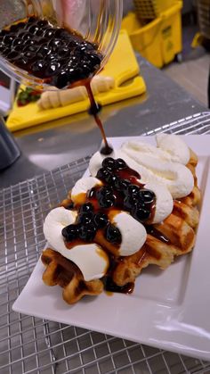 a waffle topped with bananas and blueberries is being drizzled with syrup