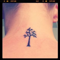 a small tree tattoo on the back of a woman's neck