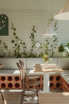 a table and chairs in a room with plants on the wall