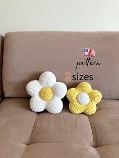 two crocheted flowers sitting on the back of a couch next to each other