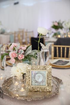 the table is set with flowers, candles and an old clock on it's stand