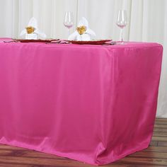 the table is covered with pink cloth and place settings for two people to sit at