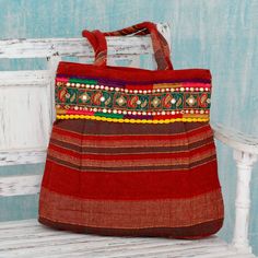 a red bag sitting on top of a wooden bench next to a white bench with a blue wall behind it