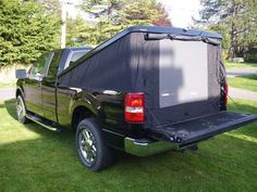 the back end of a pickup truck with its bed open and covered in black tarp