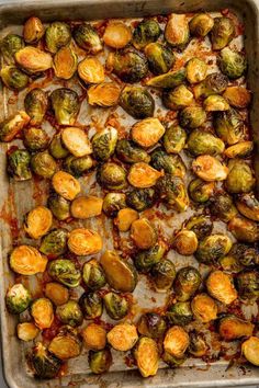 roasted brussel sprouts in a baking pan with melted cheese and sauce