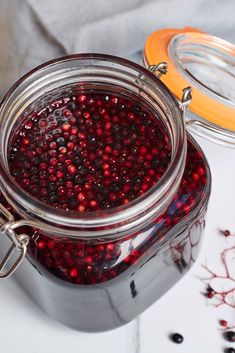 a glass jar filled with cranberry sauce on top of a table